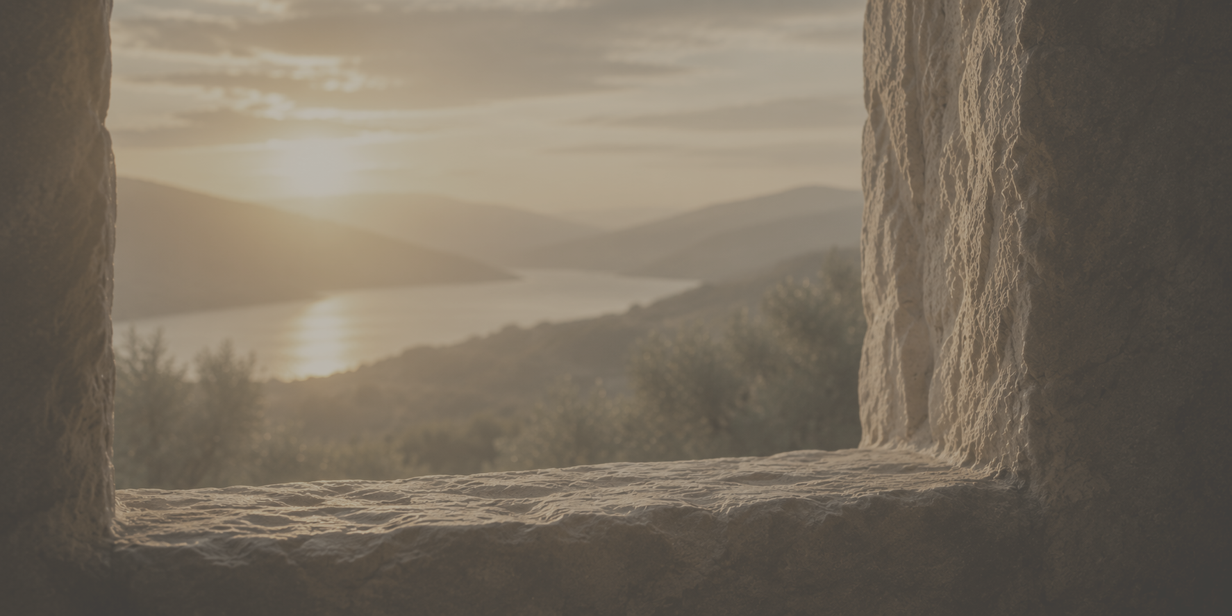 Sunrise over hills and a winding river, seen through a worn stone window — a threshold image.